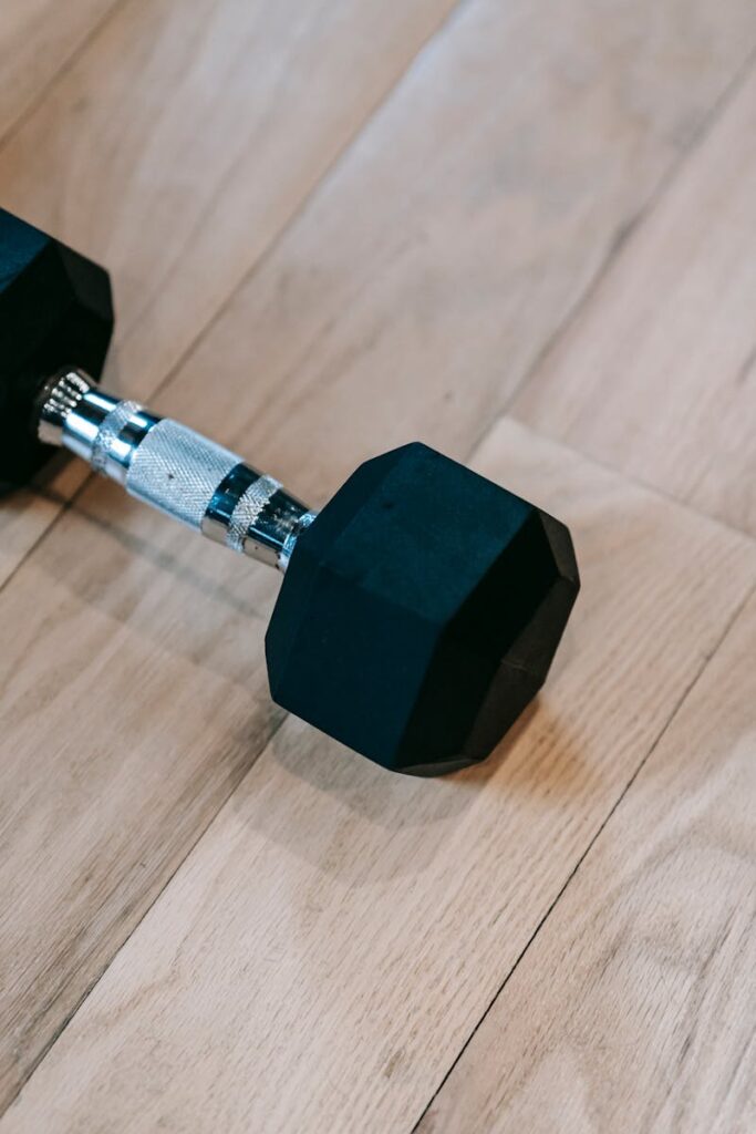 Close-up of a hex dumbbell on a wooden gym floor, ideal for weightlifting and strength training.